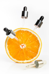 Vitamin C in the form of serum in pipettes, taken from an orange for youthful skin.