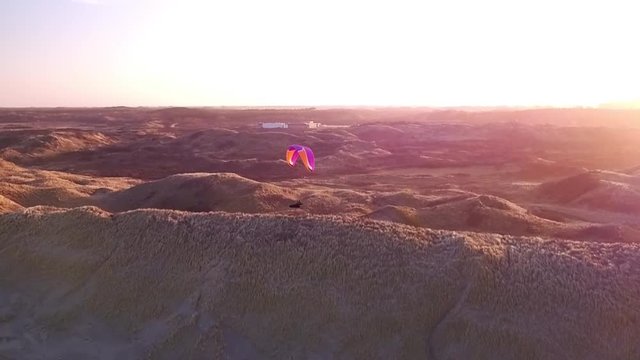 Drone/Aerial shot of a parapenter flying over the duns ot the Netherlands. Shot was made by a professional drone pilot.