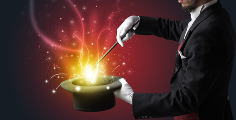 Magician hand conjure with wand  light from a black cylinder