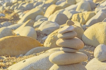 The balance of stones of light color on the rocky shore. Solar warm lighting and background.
