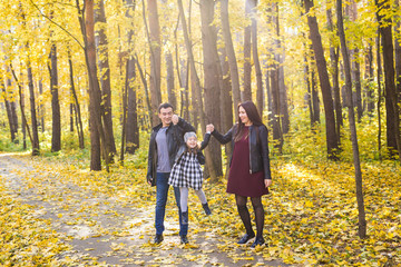 People, family and leisure concept - mixed race father and mother have fun in autumn park with their daughter