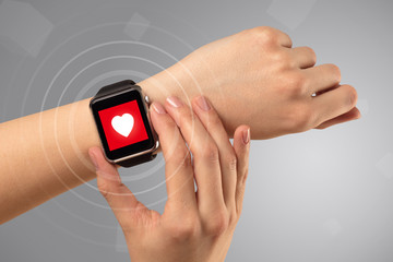 Fototapeta premium Naked female hand with smartwatch and with heart rate icon on the watch