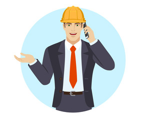 Businessman in construction helmet  gesturing and talking on the mobile phone