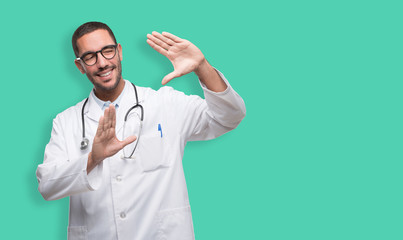 Happy young doctor doing a frame gesture with his hands