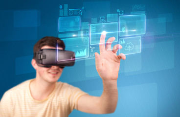 Young impressed man wearing virtual reality goggles with blue squares containing data at his fingers 