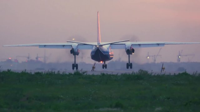Propeller airplane is landing at sunset