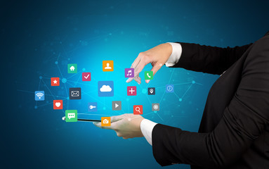 Female hand touching tablet with application icons above