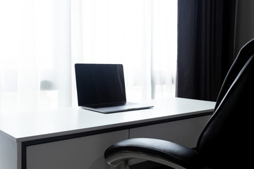 Fototapeta na wymiar Desk Workplace with laptop on white table and black chair at home office