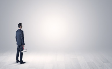 Man standing with his back in an empty room with object in his hand