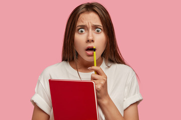 Indoor shot of shocked European woman stares with surprisement at camera, keeps mouth opened, holds...