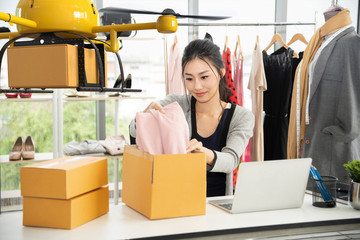 Young asian women packing cloth on box for delivery to customer by air drone, Small business with...