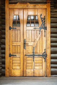 Outdoor front view of a naturally wood finished door entrence. Rustic traditional decorative pattern with iron fittings.