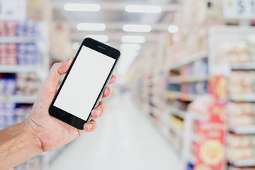 Man hands using smart phone with blurred supermarket store background. Blank screen for graphics display montage.