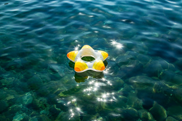 Little boy with life ring, swimming ring on the transparent water on the center of the picture