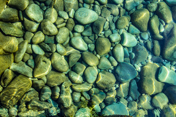 Pebbles in stream, transparent water as abstract background