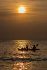 Fototapeta premium A man and a woman ride the boat in the rays of the setting sun