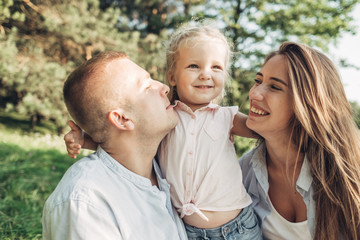 Young Adult Couple with Their Little Daughter Having Fun in the Park Outside the City, Family Weekend Picnic Concept, Three People Enjoying Summer Time