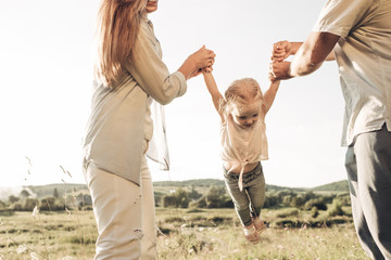 Young Adult Couple with Their Little Daughter Having Fun in the Park Outside the City, Family Weekend Picnic Concept, Three People Enjoying Summer Time