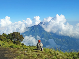 Fototapeta na wymiar Man enjoying the view of Merapi Mountain from Merbabu, Central Java, Indonesia