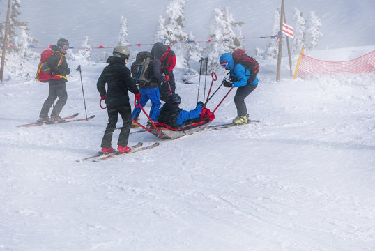 Ski rescue team with slide stretcher, brings help to ski during bad weather conditions.