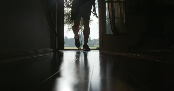 A couple returning after a morning jog are silhouetted by the morning light as they open their front door and enter in.