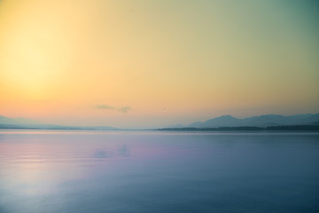 A beautiful, calm morning landscape of lake and mountains in the distance. Colorful summer scenery with mountain lake in dawn. Tatra mountains in Slovakia, Europe.