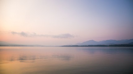 A beautiful, calm morning landscape of lake and mountains in the distance. Colorful summer scenery...