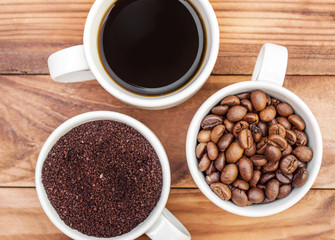 Cups of coffee drink, ground coffee and beans on the wooden background. Top view. Close up.