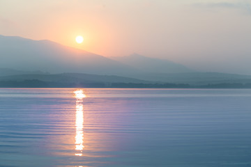 Obraz premium A beautiful, calm morning landscape of lake and mountains in the distance. Colorful summer scenery with mountain lake in dawn. Tatra mountains in Slovakia, Europe.