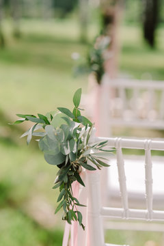 Wooden chairs at a wedding. The chairs for guests decorated with buttonholes and tapes