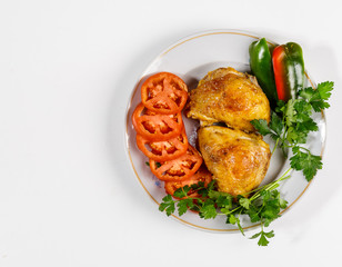 Fried chicken with vegetables on a round plate on a white background.