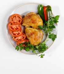 Fried chicken with vegetables on a round plate on a white background.
