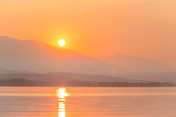 A beautiful sunrise over the lake with mountains in distance. Morning landscape in warm tones. Tatra mountains in Slovakia, Europe.