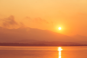 A beautiful sunrise over the lake with mountains in distance. Morning landscape in warm tones. Tatra mountains in Slovakia, Europe.