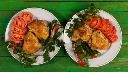 Fried chicken with vegetables on a round plate on a green wooden table