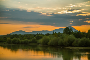 A beautiful, colorful sunset landscape with lake, mountain and forest. Natural evening scenery over the mountain lake in summer. Tatra mountains in Slovakia, Europe.