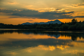 A beautiful, colorful sunset landscape with lake, mountain and forest. Natural evening scenery over the mountain lake in summer. Tatra mountains in Slovakia, Europe.