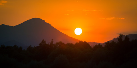 Fototapeta premium A beautiful, colorful sunset landscape with lake, mountain and forest. Natural evening scenery over the mountain lake in summer. Tatra mountains in Slovakia, Europe.
