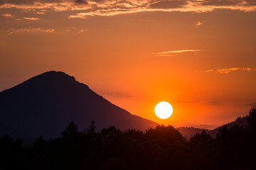 A beautiful, colorful sunset landscape with lake, mountain and forest. Natural evening scenery over the mountain lake in summer. Tatra mountains in Slovakia, Europe.