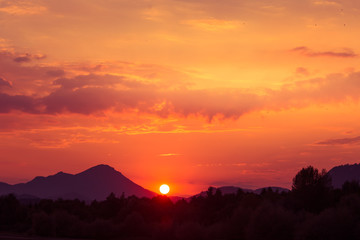 A beautiful, colorful sunset over the mountains, lake and forest in purple tones. Abstract, bright landscape. Tatra mountains in Slovakia, Europe.