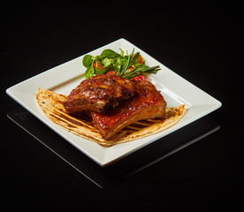 Pork ribs on a white plate with a black photo 