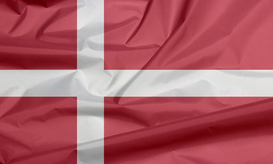 Fototapeta premium Fabric flag of Denmark. Crease of Danish flag background, red with a white Scandinavian cross that extends to the edges of the flag.