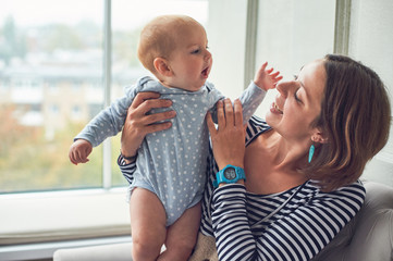 mother with an 8 month old baby sitting on a sofa at home