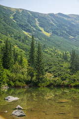 A beautiful, clean lake in the mountain valley in calm, sunny day. Mountain landscape with water in summer. Tatry mountains in Slovakia, Europe.