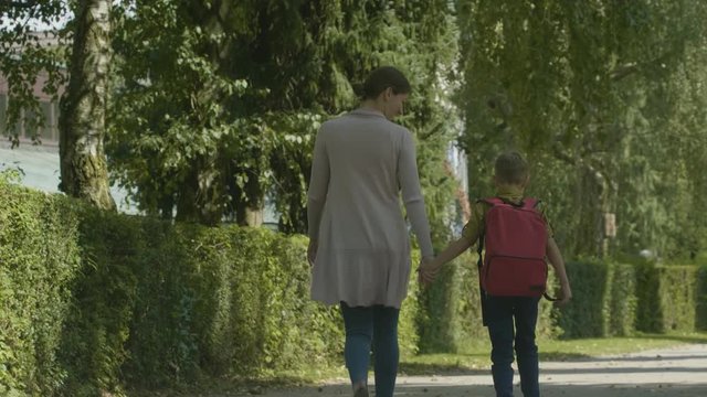 Full shot of mother walking her son to school in autumn