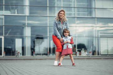 Beautiful Young Mother with Small Stylish Daughter Walks Through City Together