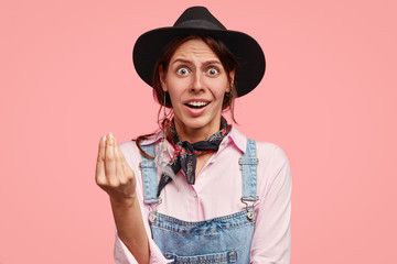 Indignant surprised young Caucasian woman keeps fingers together, being astonished with Italian...
