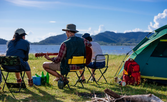 Back camping camp in nature happy friends group playing guitar in summer