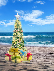 Decorated Christmas tree on sandy beach over sea with suny sky