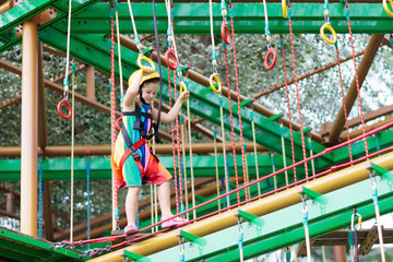 Fototapeta premium Child in adventure park. Kids climbing rope trail.